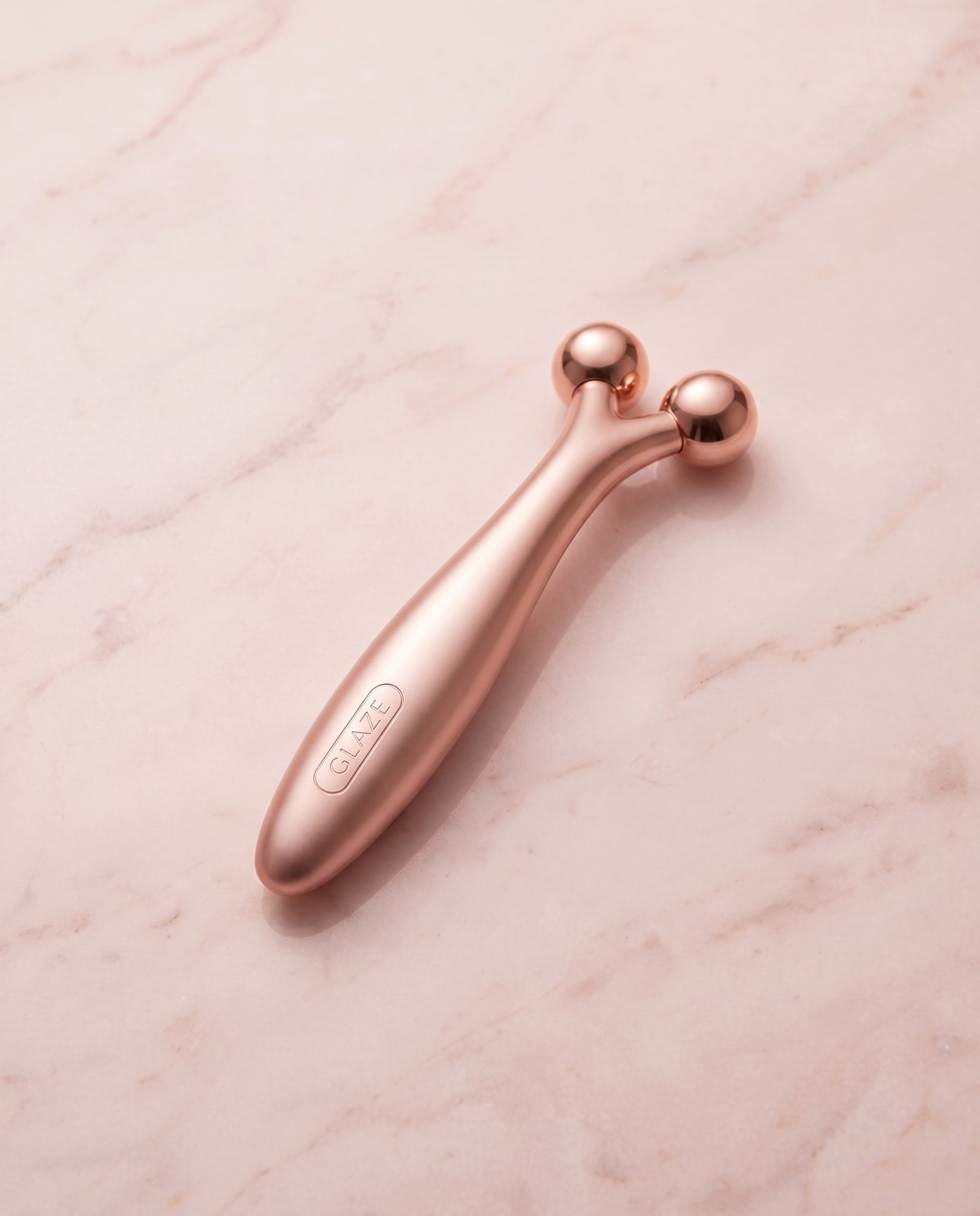 Glaze microcurrent wand, rose gold, on a dark surface